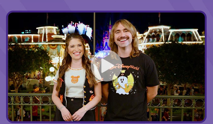 play button overlay Inside Disney hosts standing in front of Cinderella Castle lit up at night during Halloween celebration.