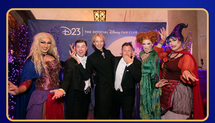 Fans dressed as Sanderson Sisters posing with guests at D23 Halloween event.