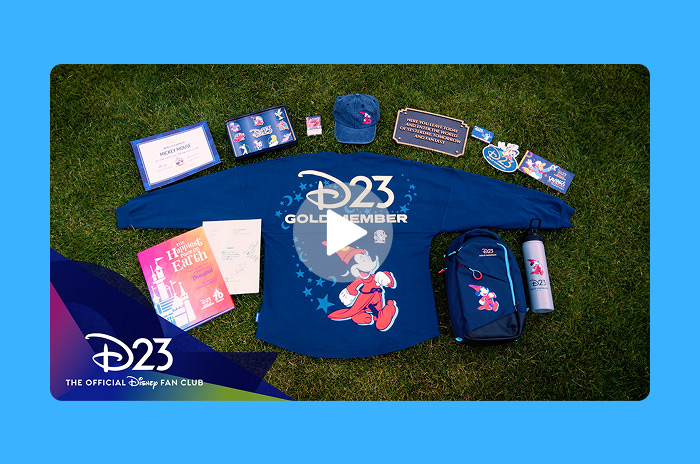 D23 Gold Member kit displayed on grass with exclusive items including shirt,backpack, water bottle, and collectibles.