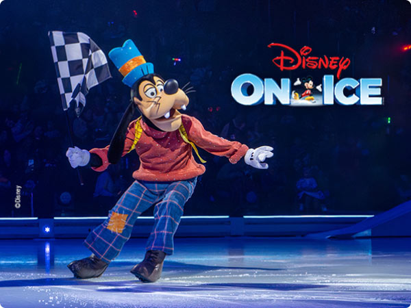 Goofy Skates across the ice holding a checkered flag during a Disney on Ice performance.