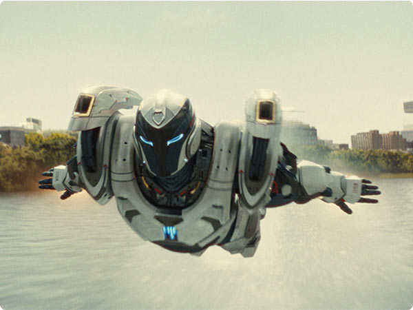 Sleek white-and-black armored suit with blue lights soars low over a river