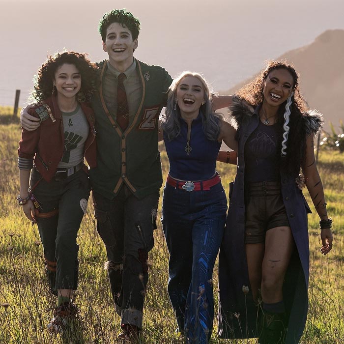 Zed, Addison and friends from Disney Zombies grin arm-in-arm while strolling through a son-drenched meadow.