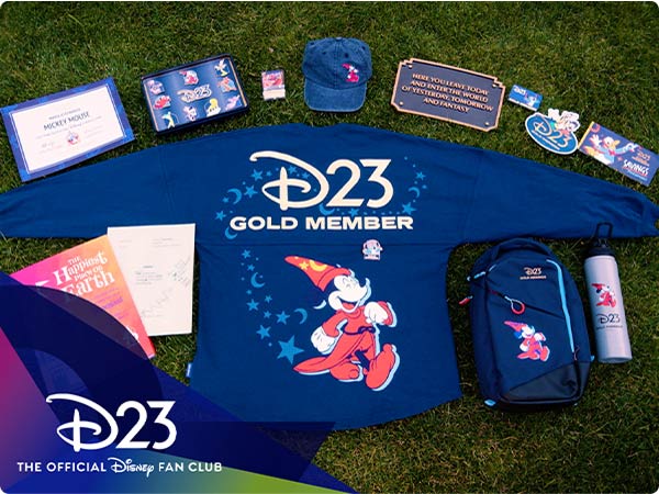 Flay lay on grass: blue spirit jersey reads “D23 Gold Member,” surrounded by certificate, book, cap, backpack, bottle and other official D23 fan-club merchandise.
