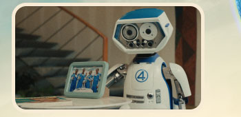 H.E.R.B.I.E robot stands beside framed photo showing four blue-suited heroes (Reed Richards, Sue Storm, Johnny Storm and Ben Grimm).
