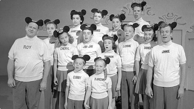 Vintage black-and-white photo of original Mickey Mouse Club cast wearing Mickey ear hats.