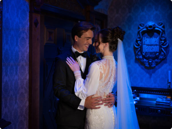 Bride and groom embrace in Haunted Mansion-themed wedding photo inside the Haunted Mansion parlor attraction Disney Destiny.
