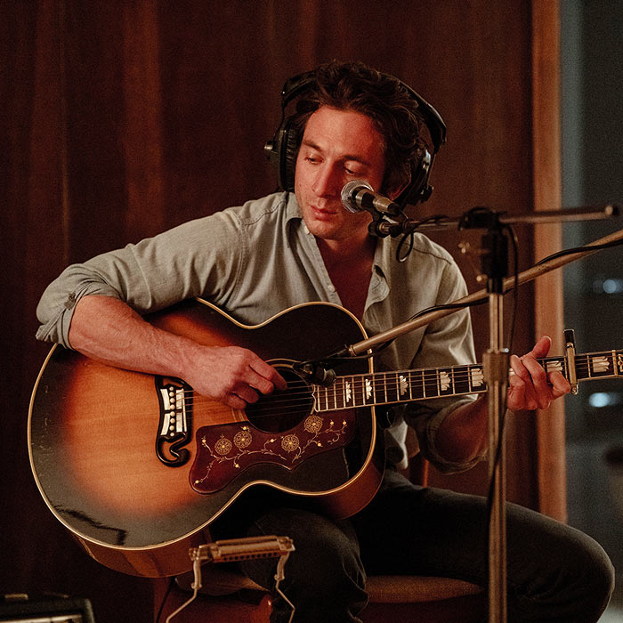 Jeremy Allen White as Springsteen recording with acoustic guitar.