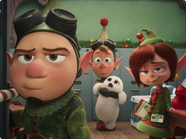 Elves from Disney’s Prep & Landing stand in a holiday workshop beside a plush white seal toy.