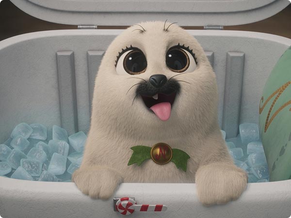 Cute white seal pops from an ice-filled cooler, wearing a holly collar with a gold “N”