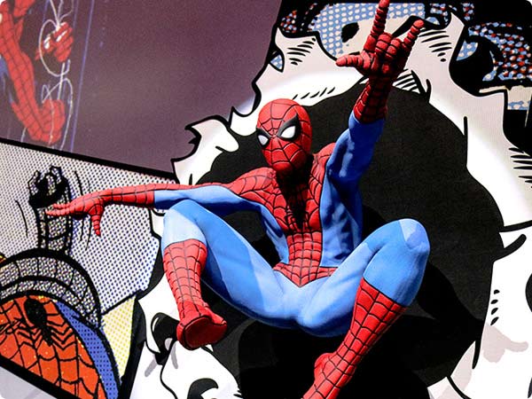 Spider-man crouches against comic book backdrop, shooting web pose.