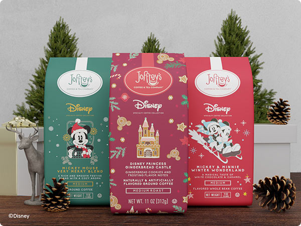 Holiday-themed Joffrey's Coffee bags featuring Mickey Mouse, Disney Princess Gingerbread Castle, and Mickey & Minnie Winter Wonderland blends displayed with pinecones and mini trees.
