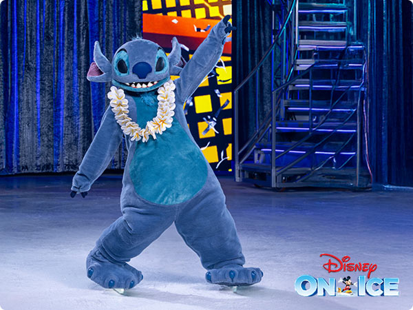 Stitch skating onstage wearing a white le, with colorful lights and the Disney On Ice logo in the corner.