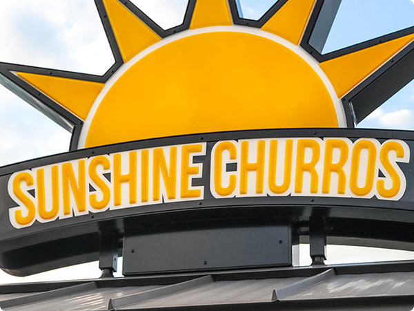 Sunshine Churros sign beneath a bright yellow sun emblem.